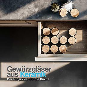 Elegante schwarze Keramik Gewürzbehälter mit Korkdeckel, ordentlich in einer Küchenschublade arrangiert – stilvolle Aufbewahrung für Kräuter und Gewürze.