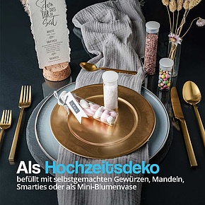 Elegante Hochzeitsdekoration mit Reagenzgläsern, gefüllt mit Smarties, Mandeln und Salz, auf einem festlich gedeckten Tisch mit goldenem Besteck