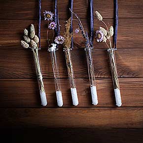 An Ringen hängende Bördelrand-Gläser mit Trockenblumen, Sand und Schnur